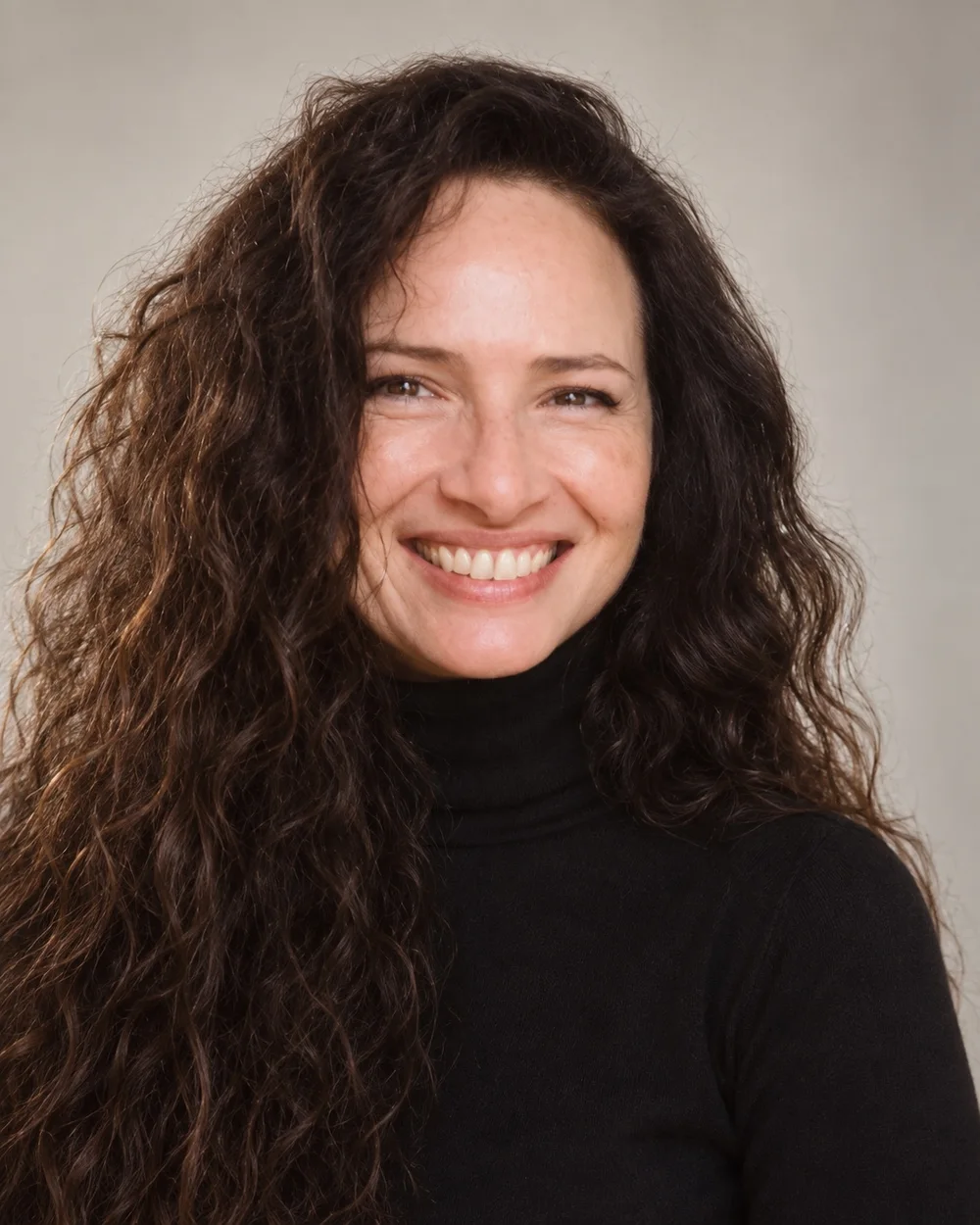 Retrato en color de Sandra María Rojas Montes, con jersey negro de cuello alto y fondo gris